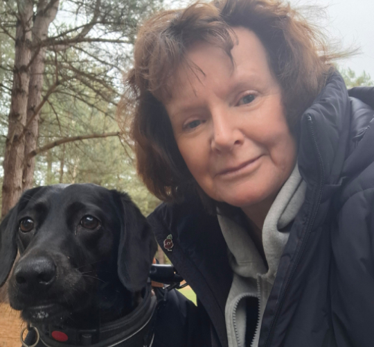 Corrinne, a previous winner, smiling next to Poppy, her black dog.